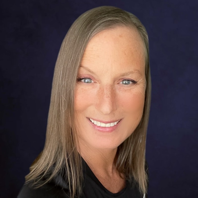 Lulu Waters, founder of Lexibl, smiling warmly. She has long blonde hair and is wearing a black top against a deep purple background.